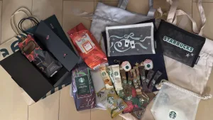 スターバックス クリスマスホリデーギフト2025の購入品コレクション。メッシュポーチ（白・黒）、限定ギフトラッピングバッグ、ドローストリングポーチ、リザーブコーヒー豆が写っている。